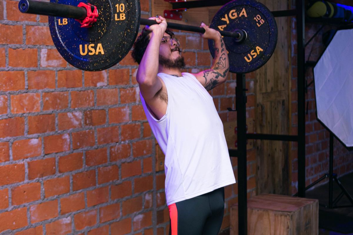 Homem levantando barra com anilhas em academia
